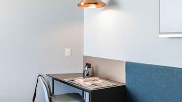 A modern room with a blue sofa, a small table, a chair, and a pendant light.