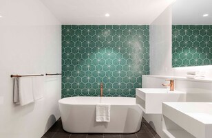 A modern bathroom with a freestanding bathtub, a white sink, and a large mirror.