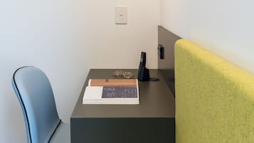 A workspace with a desk, a chair, a sofa, and a pendant light.