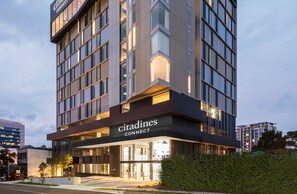 Un hôtel moderne, reconnaissable à son enseigne « Citadines CONNECT » bien visible, à ses grandes fenêtres et à son entrée bien éclairée.
