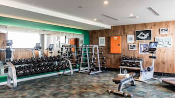 A gym with various exercise equipment, including dumbbells, weight machines, and cardio machines.