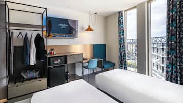 Una habitación de hotel con dos camas, un escritorio, una silla, un televisor y un armario.