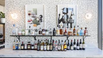A bar area with a mosaic wall, two framed artworks, and a variety of liquor bottles.