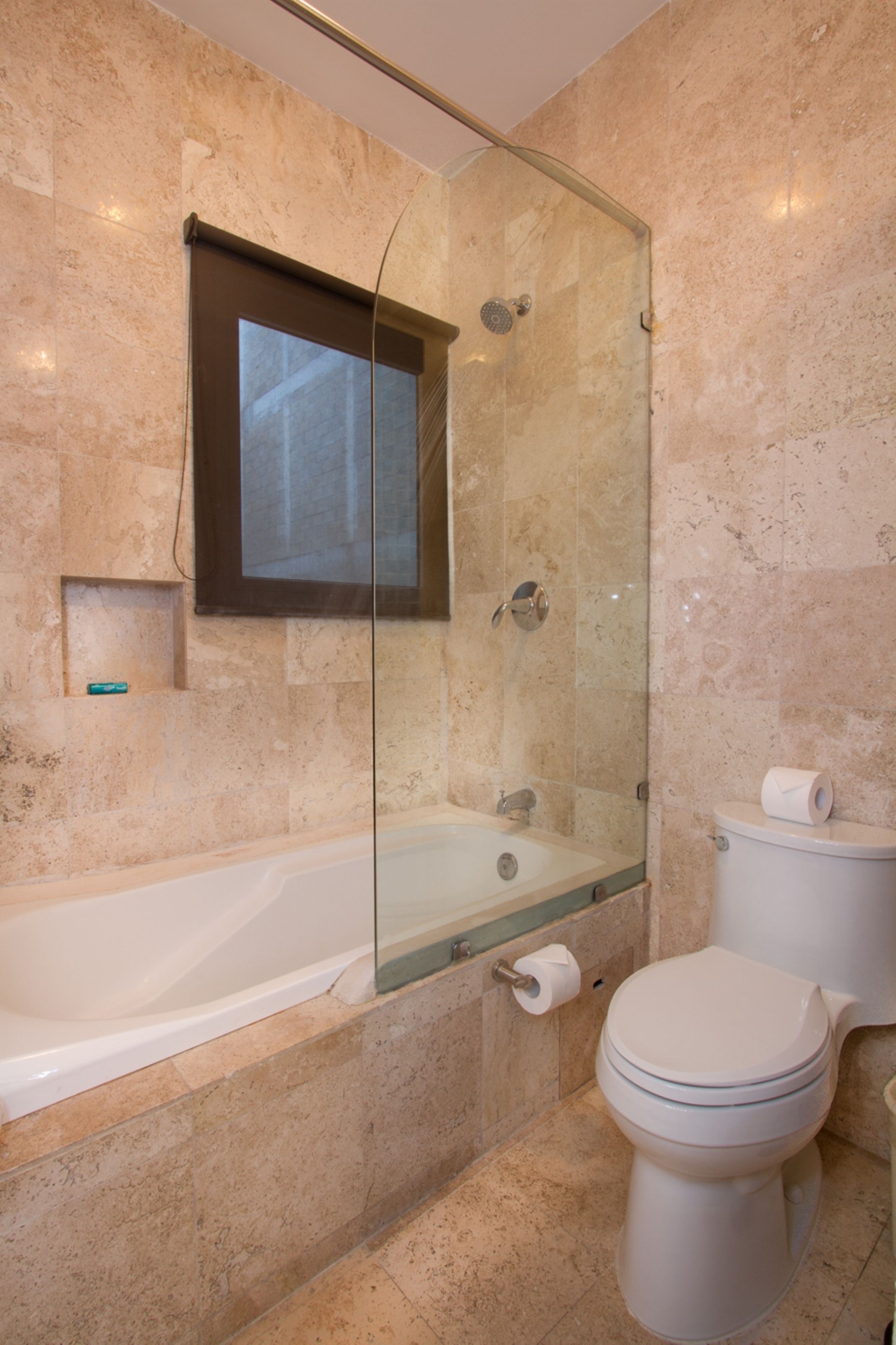 A modern bathroom with a glass-enclosed shower, a bathtub, and a toilet.