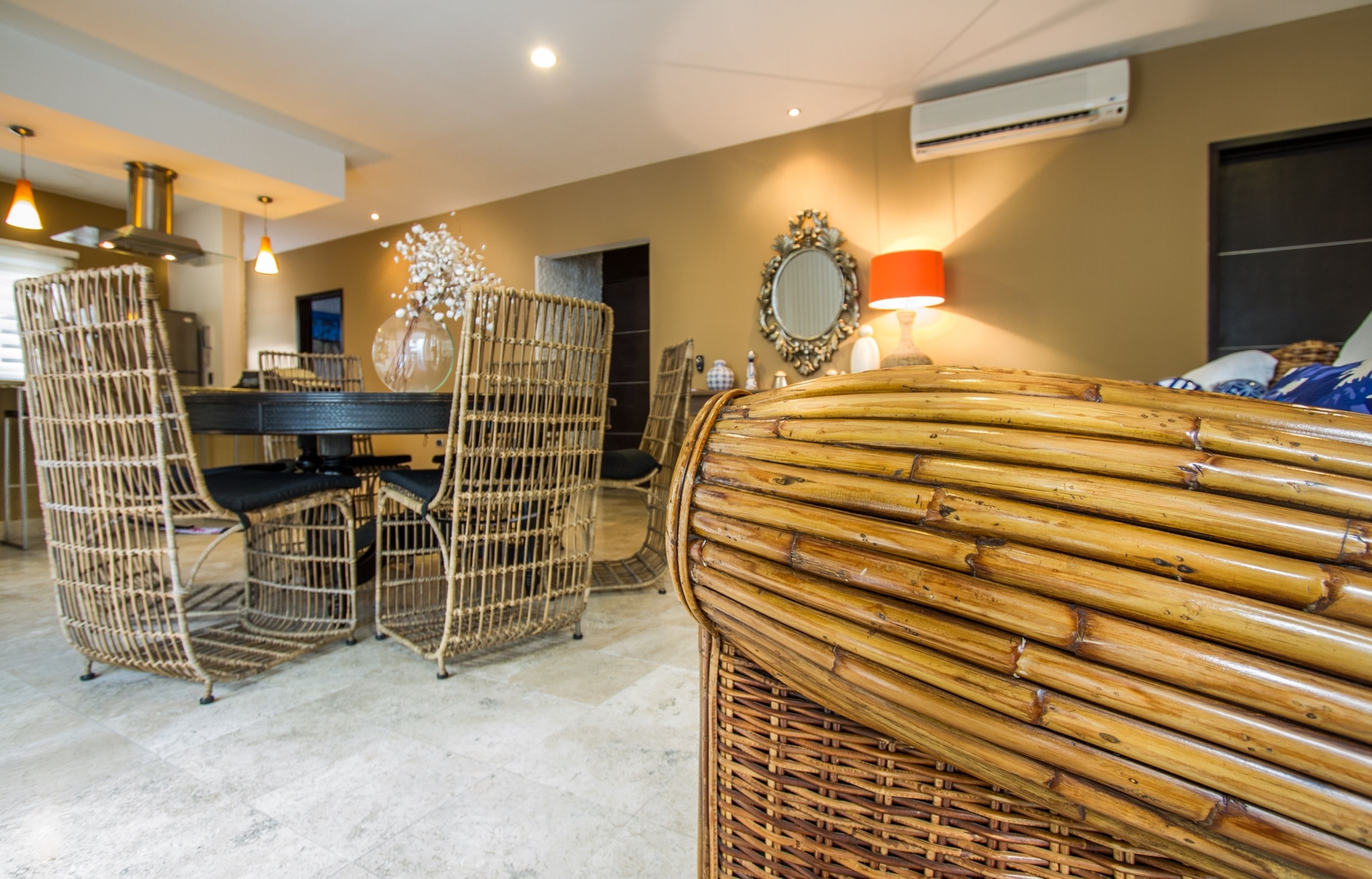 Une pièce meublée de meubles en osier, avec une table à manger et un miroir au mur.