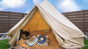 A tent with a sleeping area, a lantern, and decorative pillows.