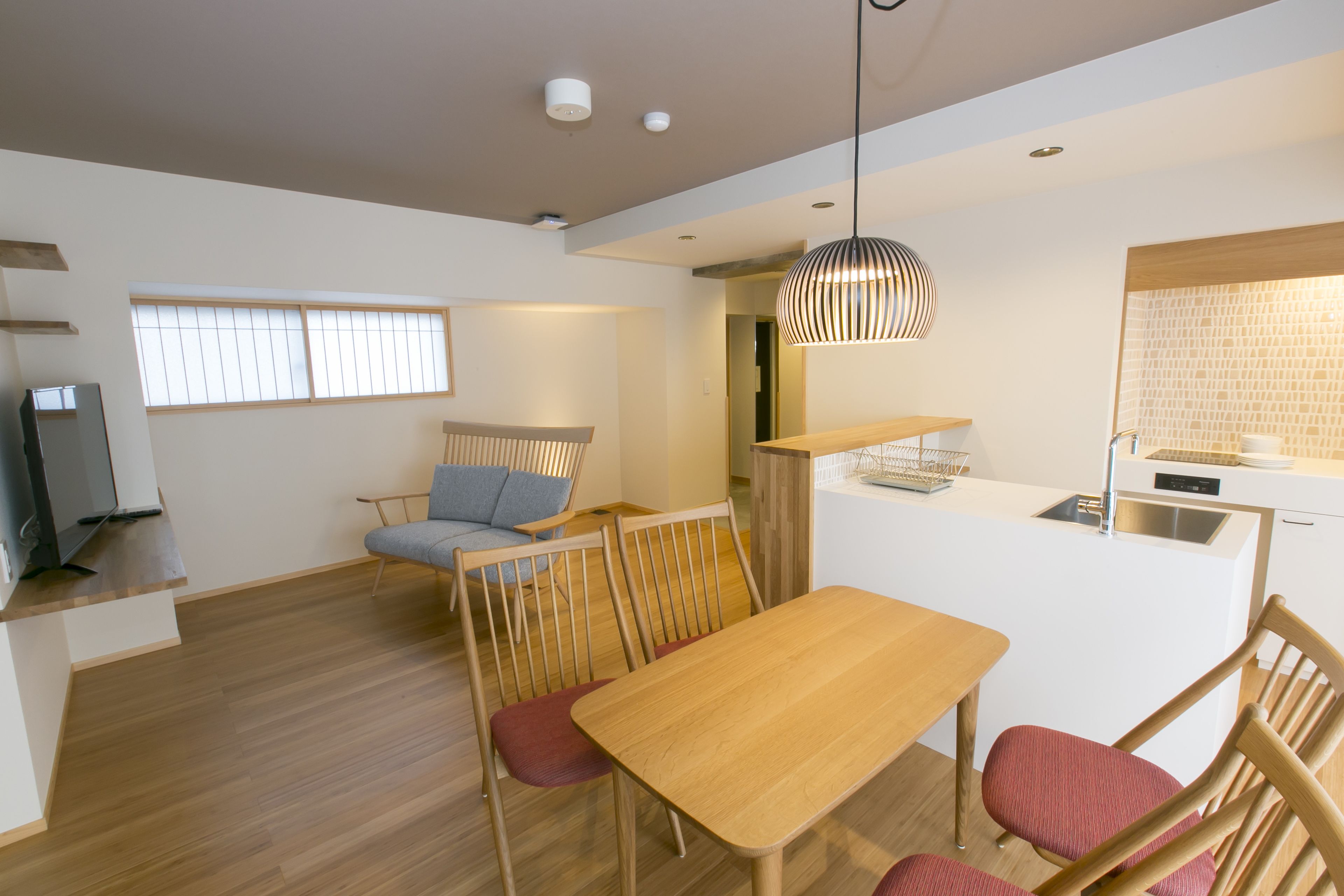 A modern kitchen with a wooden island, a dining area with a table and chairs, and a seating area with a sofa and chairs.