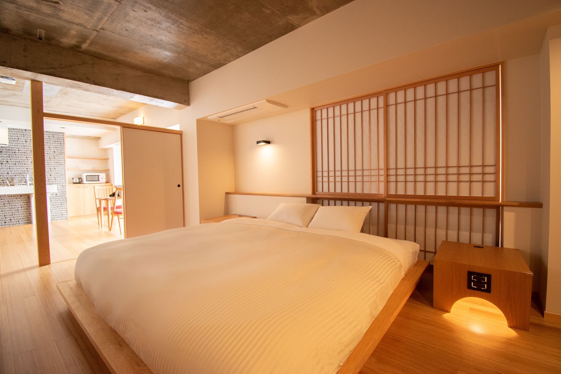 A modern bedroom with a large bed, wooden headboard, and a shoji screen.