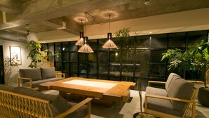 A modern living room with a sofa, armchairs, a wooden coffee table, and hanging pendant lights.