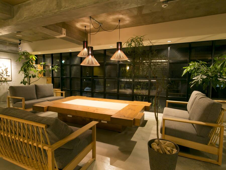 A modern living room with a sofa, armchairs, a wooden coffee table, and hanging pendant lights.