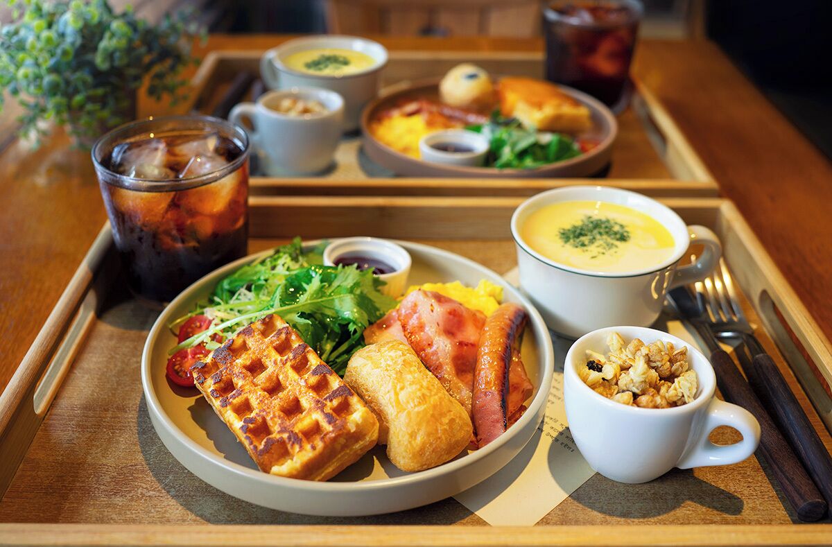 A tray with waffles, soup, and a cup of coffee.