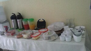 A buffet table with various food containers, cups, and utensils. - Pousada Cariri (Juazeiro do Norte)