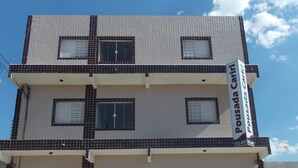 A multi-story building with a tiled facade, a prominent sign, and a door with barred windows. - Pousada Cariri (Juazeiro do Norte)
