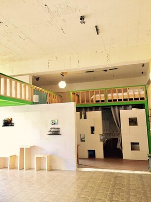 Une pièce avec un plafond haut, un escalier et une structure de lit superposé.