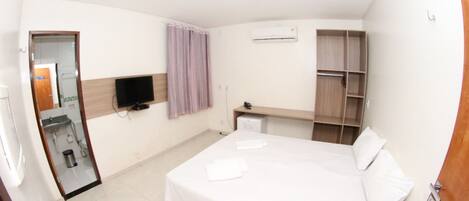 A hotel room with a bed, a television, a wardrobe, and a mirror.