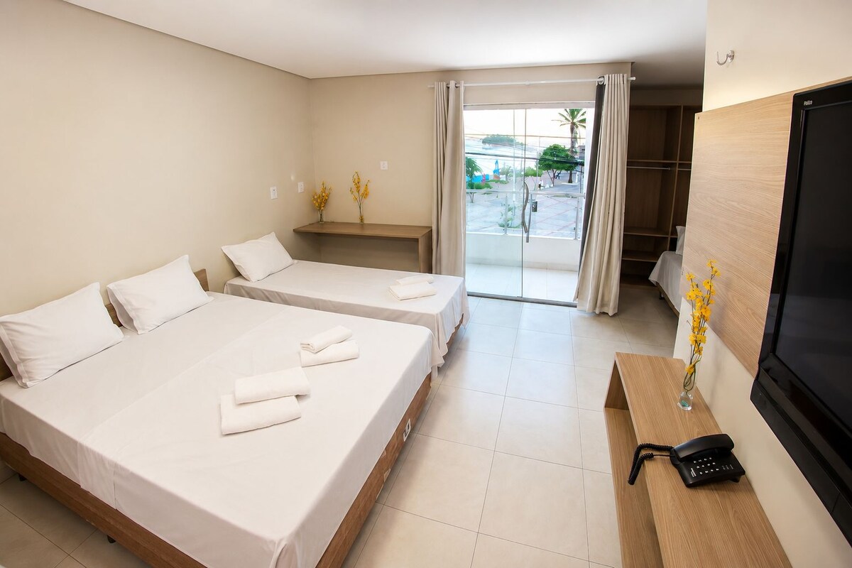 Ein Hotelzimmer mit zwei Betten, einem Fernseher, einem Telefon und Blick ins Freie.