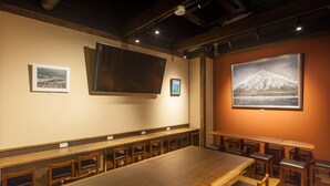 Un restaurante con una larga mesa de madera y sillas, obras de arte enmarcadas en las paredes y un cuadro grande de una montaña.