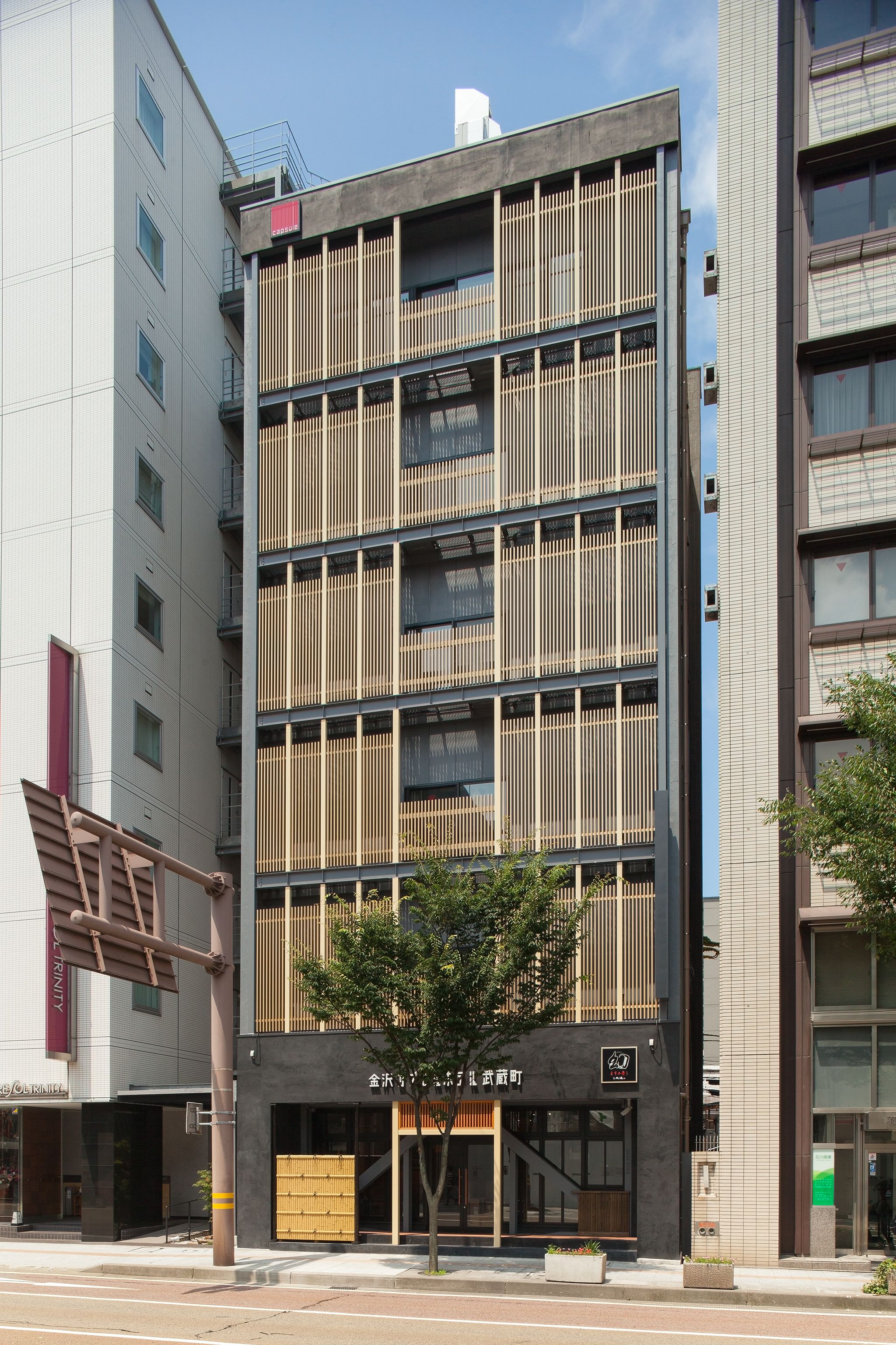 A multi-story building with a modern design, featuring vertical wooden slats on the facade and a ground-level entrance with a glass door.