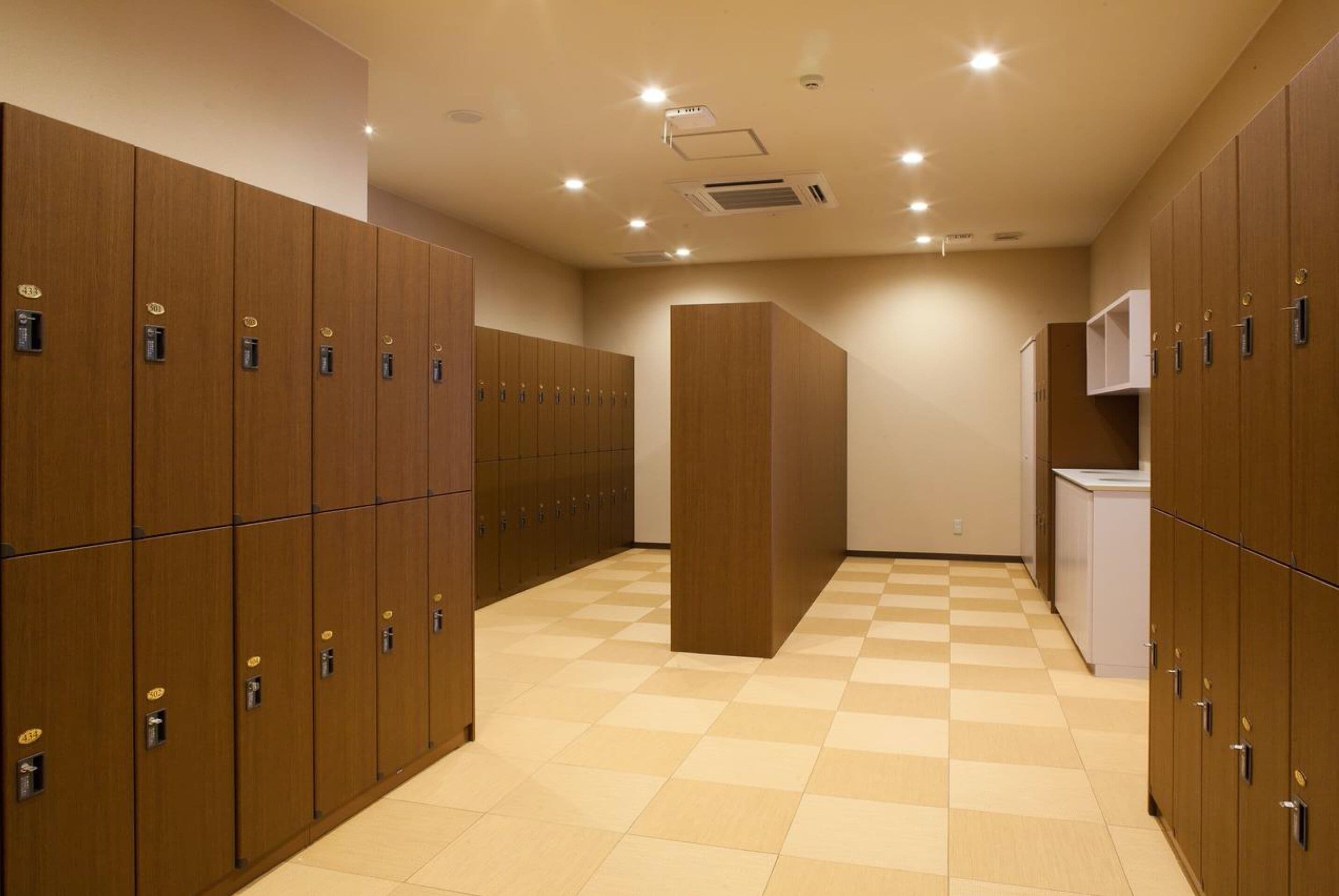 A hotel room with wooden lockers, a checkered floor, and a kitchenette area.