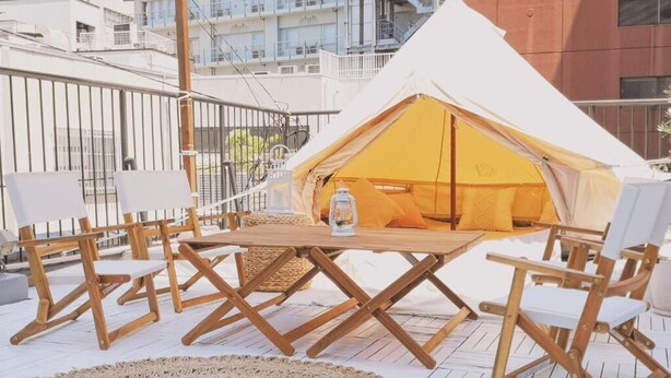 A tented outdoor seating area with a table and chairs, surrounded by a white deck and a woven mat. - Guest House Kobe Nadeshikoya - Hostel (Kobe)