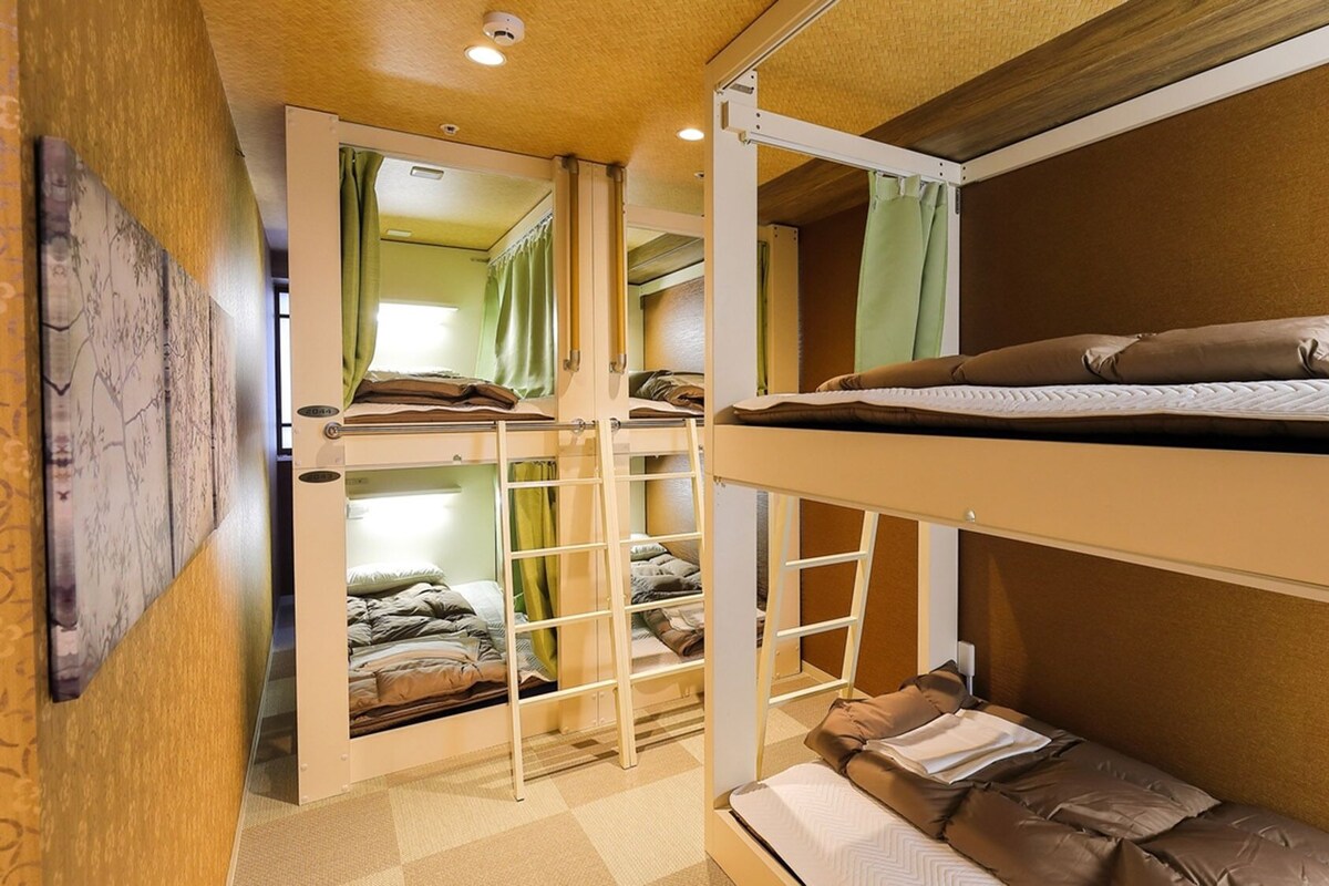 A bunk bed room with a ladder, a lower bunk with pillows, and a window with curtains.
