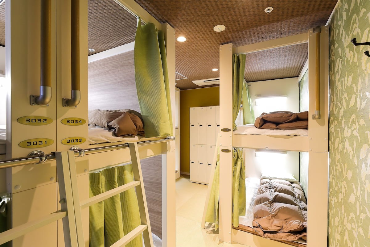 A dormitory room with bunk beds, a ladder, and lockers.