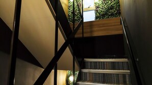 A staircase with a modern design, featuring a black metal railing and a patterned carpet. - Guest House Kobe Nadeshikoya - Hostel (Kobe)