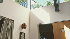 A modern interior with a wooden ceiling, large windows, and a view of greenery outside. - Atelier Café bar Seihei (Nakijin)