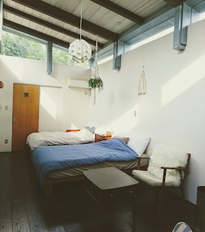 A bedroom with a bed, a chair, a hanging plant, and a window. - Atelier Café bar Seihei (Nakijin)