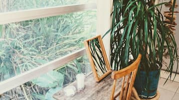 A wooden table with a chair, a potted plant, and a window with a view of greenery.