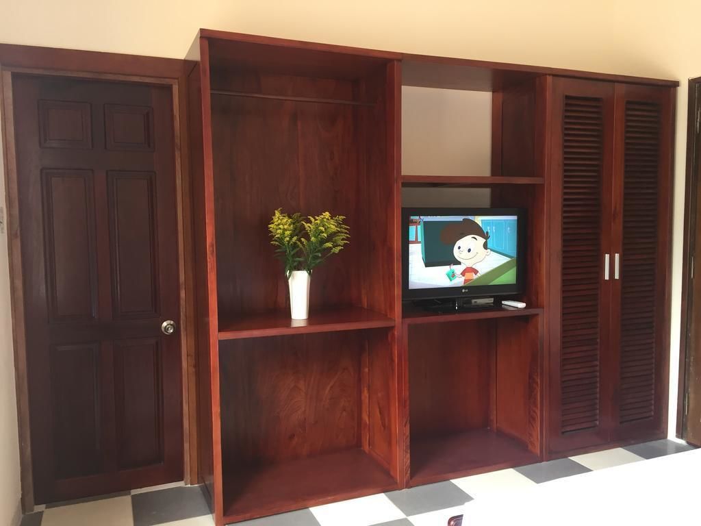 Een houten tv-meubel met een televisie, een potplant en een schuifdeur.