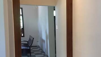A hallway with a checkered floor and a wooden-framed mirror.