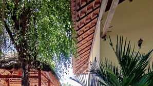 Un camino adoquinado que lleva a un espacio cubierto con un árbol y plantas en macetas.