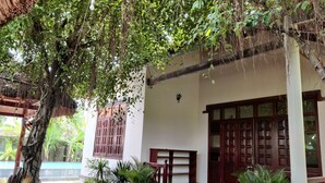 Un edificio tradicional con techo de paja, puertas de madera y una escalera que lleva a un porche cubierto.