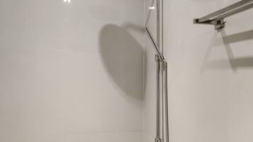 A modern shower with a handheld showerhead and a vertical rain showerhead, mounted on a wall with a chrome finish.