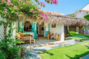 A house with a thatched roof, a porch with wooden furniture, and a garden with a lawn and a small pond. - An Bang Gate Away (Da Nang)
