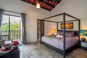 A four-poster bed with a view of greenery outside, a stone wall, and a sunset painting. - An Bang Gate Away (Da Nang)