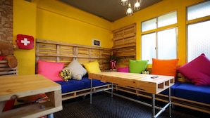 Een knus ingerichte kamer met een blauwe bank, kleurrijke kussens, een houten tafel en een Zwitserse vlag aan de muur.