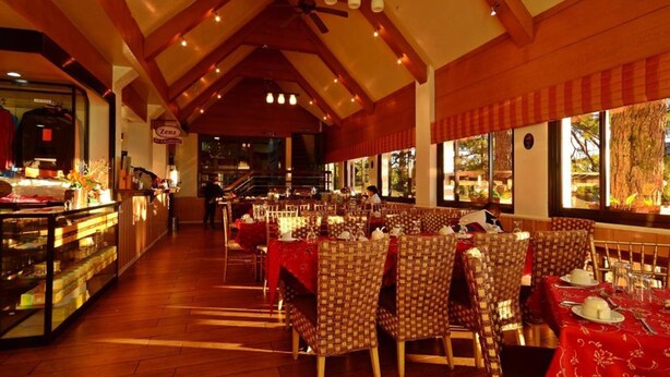 Un restaurante con vigas de madera, manteles rojos y sillas estampadas.