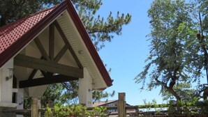 Un espacio de estar al aire libre cubierto, con bancos de madera y techo rojo.