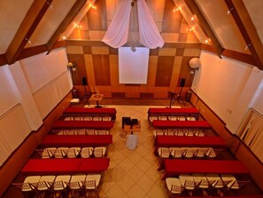 A conference room with rows of tables and chairs, wooden panel walls, and a projector screen. - Mines View Park Hotel (Baguio)