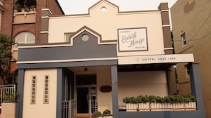 A two-story building with a sign for 'Coogee Beach House Hostel' and a contact number. - Coogee Beach House - Hostel (Coogee)