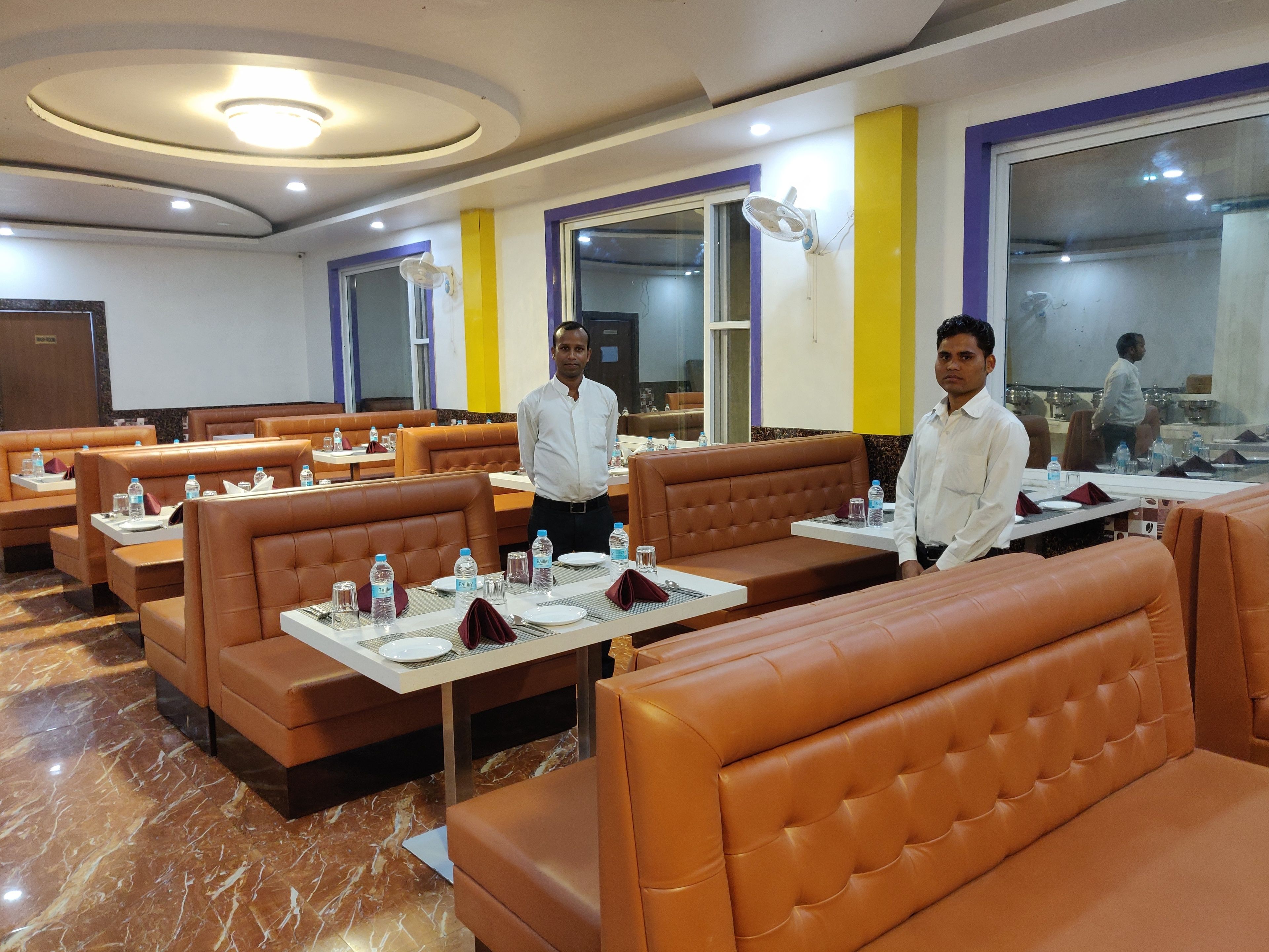 A restaurant with brown leather booths, white tables, and a marble floor.