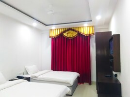 Una habitación de hotel con dos camas, televisión y armario.