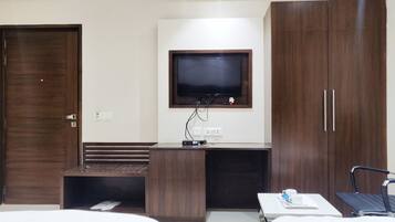 Quarto de hotel com cama, escrivaninha, televisão e guarda-roupa.