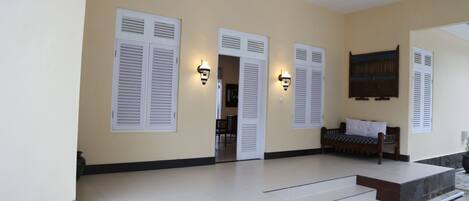 A hotel entrance with a covered porch, white shutters, and a bench.