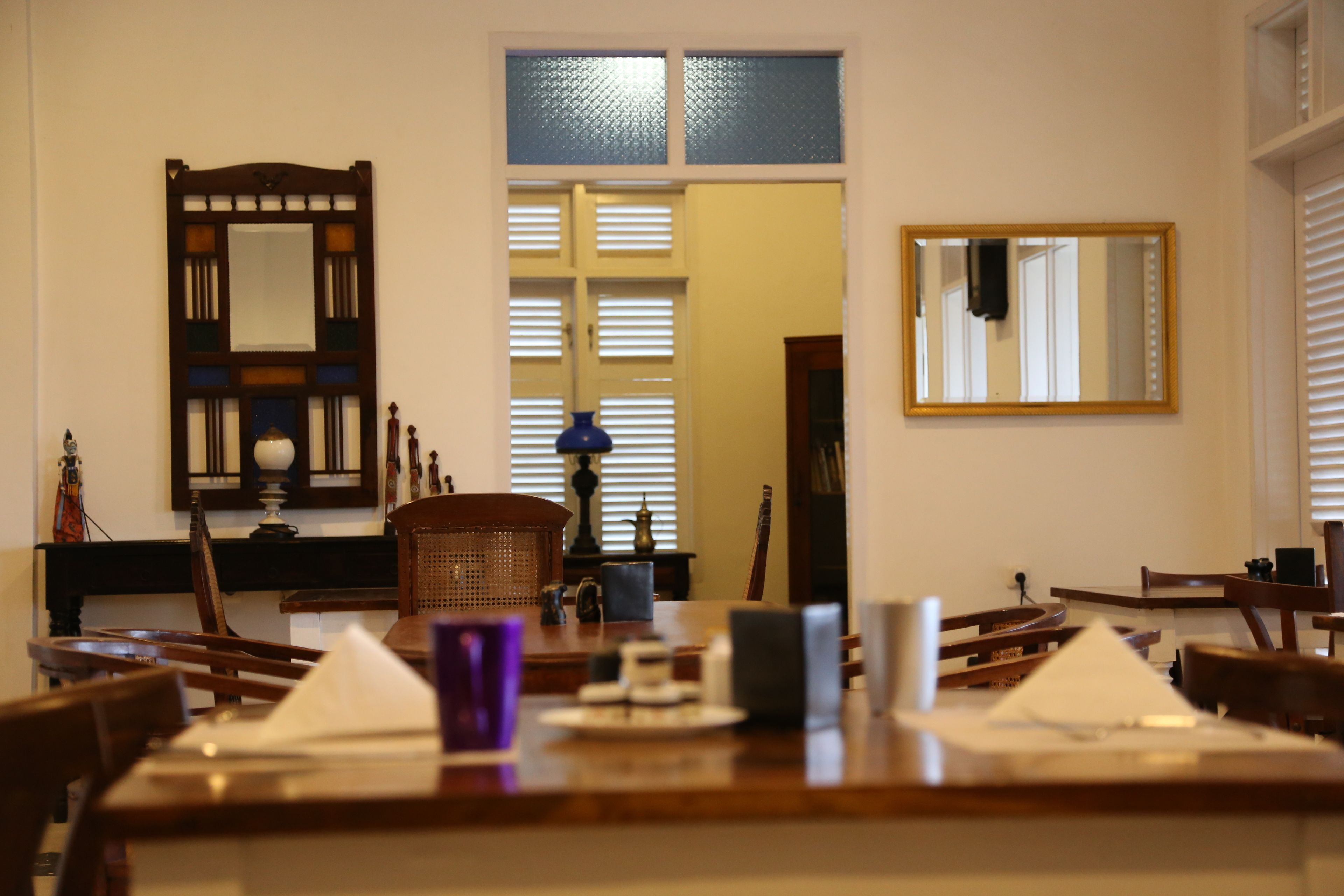 A dining area with wooden furniture, a table set with white napkins, and a blue vase.