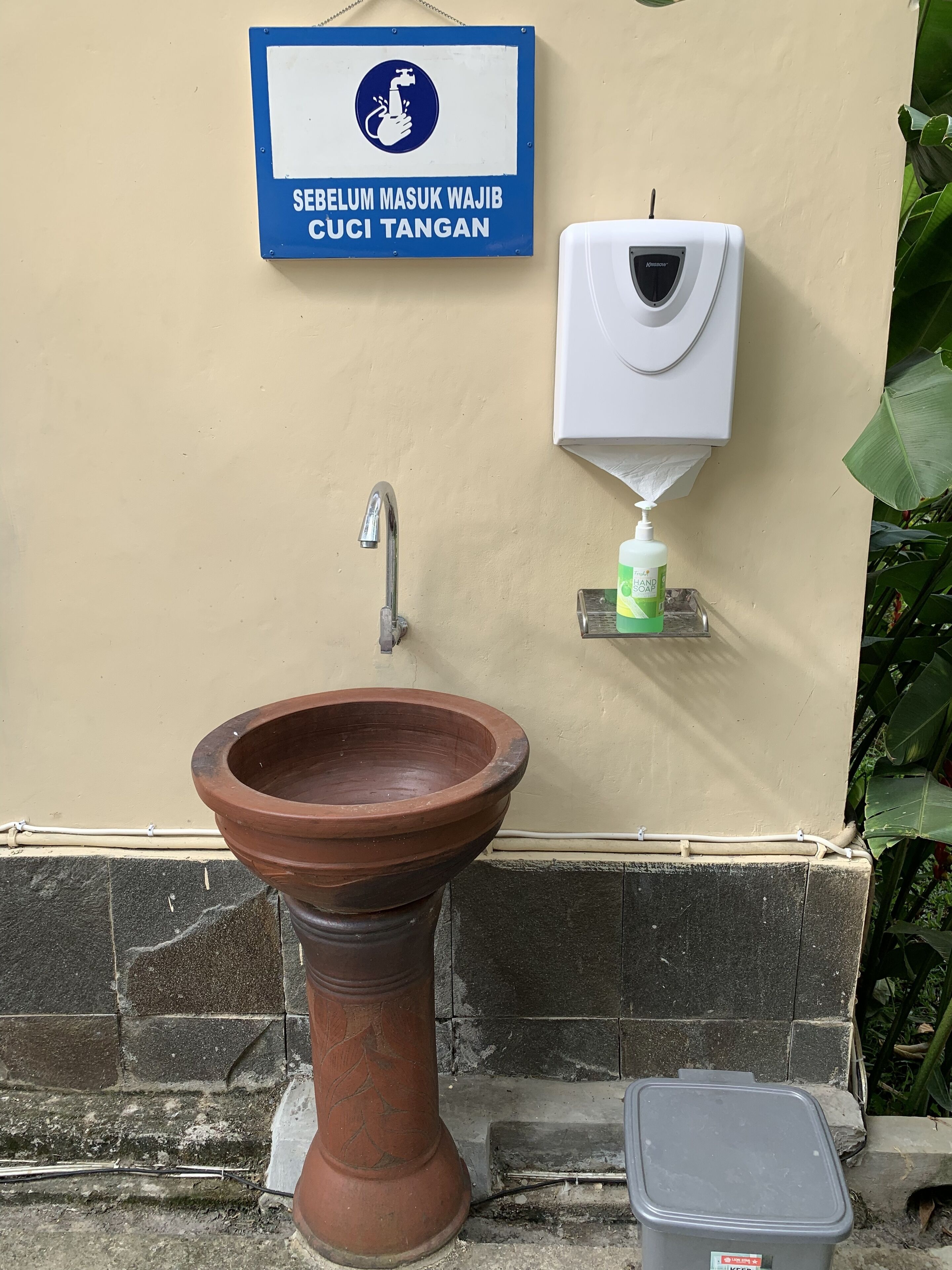 A public restroom with a hand soap dispenser, a hand dryer, and a traditional basin.
