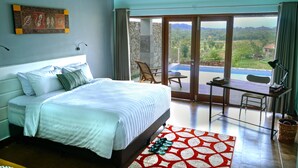 Un dormitorio con una cama grande, un escritorio y vistas a un balcón con piscina.