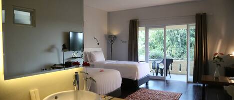 Habitación de hotel con una cama grande, un baño con lavamanos y un balcón con mesa y sillas.